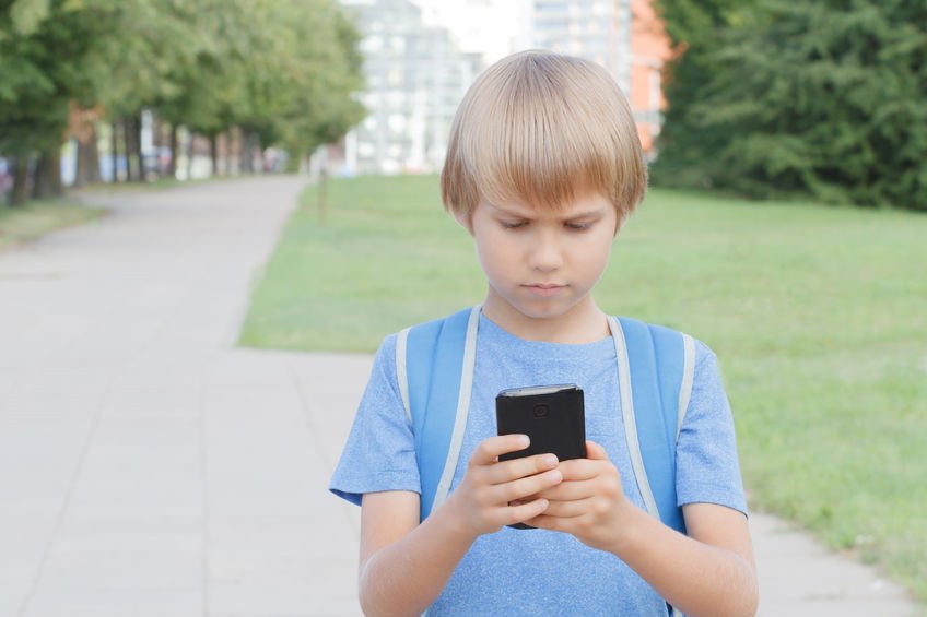 Pojke spelar Pokémon GO i en park